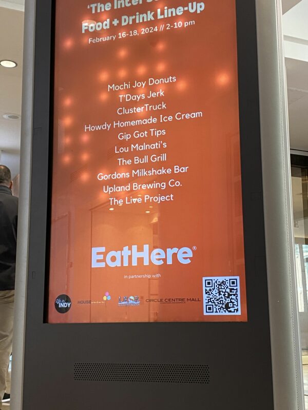 Orange digital kiosk display with white writing for "EatHere" at The Intersection at Circle Centre Mall.