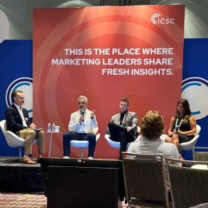 Four panelists on a stage during the ICSC Specialty conference; a red backdrop reads: 'This is the place where marketing leaders share fresh insights'.