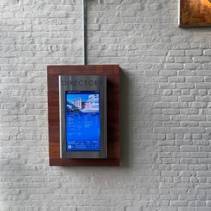 Pantella 32_ Vertical Touchscreen - TouchSource - TouchSource Digital directory display mounted on a wooden frame against a white brick wall.