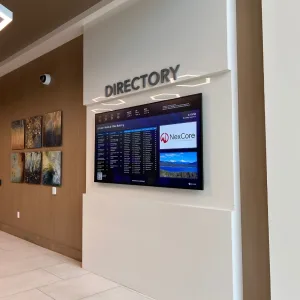 touchsource-keystone-55-inch-horizontal-static-digital-directory - TouchSource - TouchSource Directory sign with a large digital information screen mounted on a white wall in a modern lobby, showing building directory and NexCore branding.